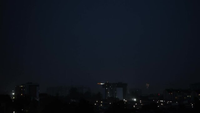 Lightning bolts flashes composition with view of night city sky with clouds. Thunderstorms, lightning over the night city. Low key lighting. Underexposed. Blue light