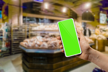 female hand using mobile phone with green screen in grocery store to check food prices