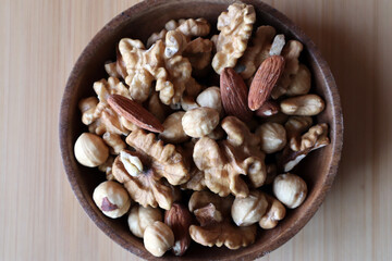 A mixture of nuts in a wooden bowl on a wooden board. Dried nuts.