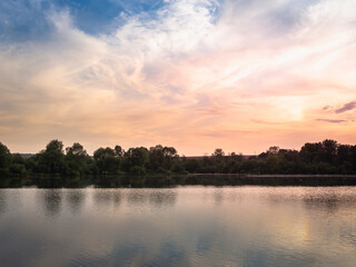 A beautiful sunset on a lake, river or pond with blue skies and clouds.