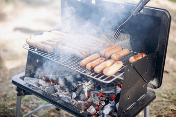 Backyard BBQ. Close-up of grilling sausages of meat on barbecue. Man preparing tasty sausages