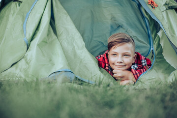 Teenager boy lying on plaid in camping tent. Family weekend outdoor.