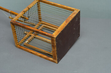 An old wooden trap for catching canaries, chirps, siskins, parrots and other birds on a gray...