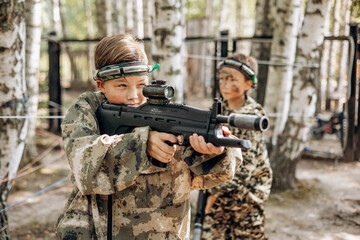Boy looking into the optical sight a weapon. Children playing laser tag shooting game in outdoor....