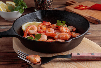 Close-up view of shrimp pinchos tapas from Spain in pan, red pepper, lemon on wooden rustic background. Selective focus.