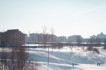 A city winter snowy landscape with several residential buildings on the background.