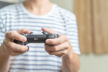 Close up hands of man, gamer using gaming controller or game pad when play video console game or online computer game at home.Gaming is relaxing from stressed and making friend, creativity, knowledge.