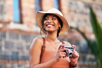 Cameras are the best traveling buddies. Shot of an attractive young woman taking pictures with a camera while exploring in a foreign city.