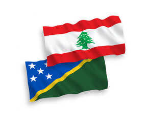 National vector fabric wave flags of Solomon Islands and Lebanon isolated on white background. 1 to 2 proportion.