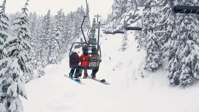 Chairlift Ride Slow Motion with Snow Flakes Falling on Mountain Terrain