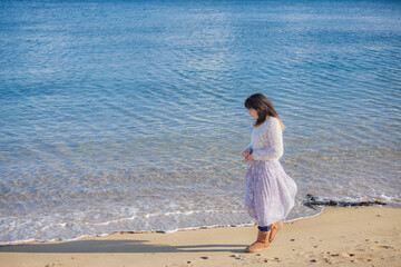 Fototapeta na wymiar 冬の海岸のビーチで散歩している若い女性の姿