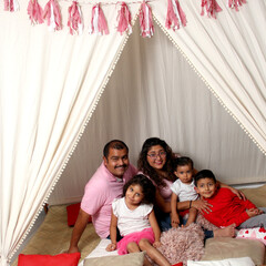 Latin family mom, dad, daughter, son play and have fun under a teepee celebrate love on their day at home because of poverty and not having expenses on the street
