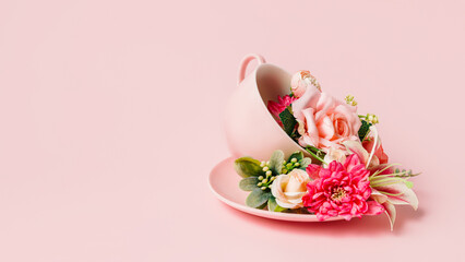 Tea cup and plate with bouquet of fresh roses and orchids on pastel pink background. Creative...