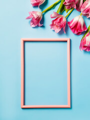 Tulip flowers bouquet and empty picture frame on pastel blue background. Creative spring bloom concept. Natural romantic love layout. Flat lay composition with space for text.