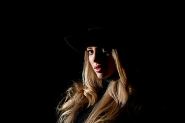 Sexy gorgeous woman with shadows on beautiful face and fashion hat on black studio. Fashion portrait of beautiful woman with dark light on face.
