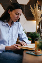 Fototapeta na wymiar brunette girl in a cafe drinking coffee, reading a book 