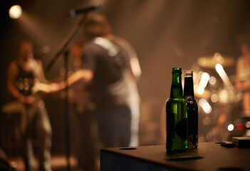 Lets have another. Two beer bottles on a table as a band plays in the background.