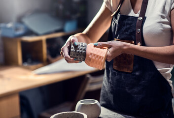 Craftswoman in apron working in her workshop making decorative concrete vase.