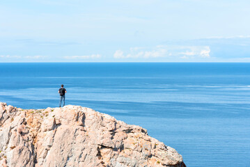Fototapeta na wymiar Man standing on a rock at the end of earth. Hiking or travel concept. Explore the great outdoors. Beauty of nature