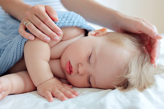 sleeping small child close-up, mother's hands cover a one-year-old baby with a blanket