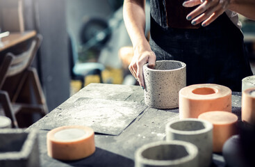 Fototapeta na wymiar Close up of craftswoman hands making decorative concrete vase in her workshop.
