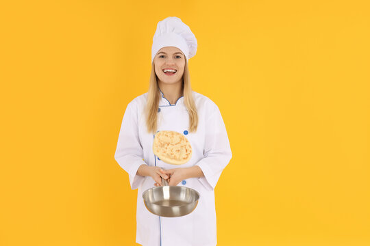 Young female chef in uniform on yellow background