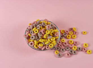 cereal breakfast rings on a pink background in a plate and scattered nearby