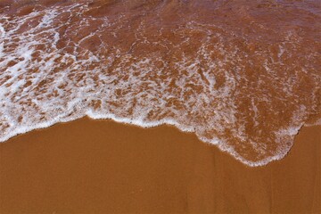 Texture of ocean water retreating over red sand typical of PEI, Canada