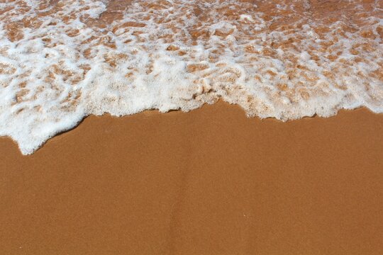 Texture of ocean water retreating over red sand typical of PEI, Canada