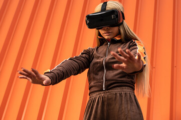 Joven mujer afroamericana usando gafas de realidad virtual en un fondo naranja