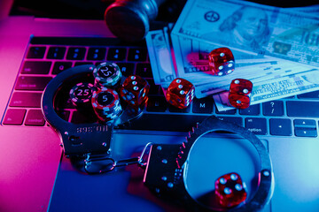 Handcuffs, wooden gavel and dice on laptop's keyboard. Online casino theme