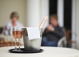 Some bubbly to commemorate the occasion. A champagne bottle and two champagne glasses on a restaurant table.