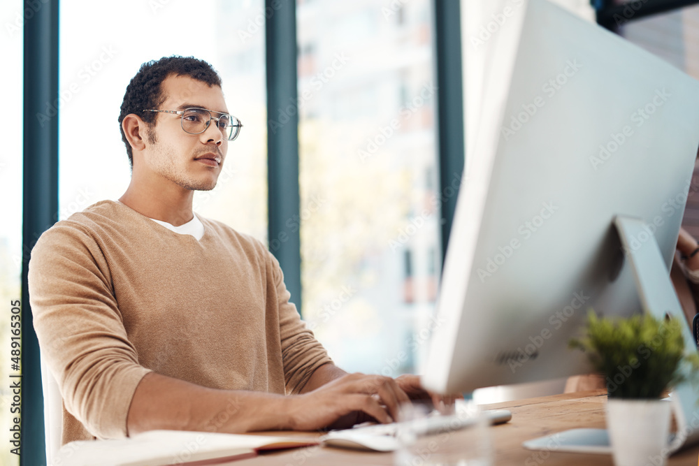 Poster keeping his focus on his goals. shot of a young designer working on a computer in an office.