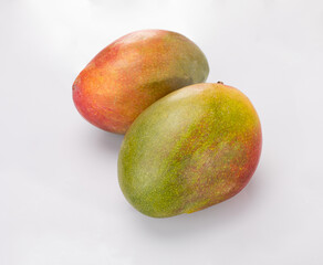 Two whole mango fruits, isolated. Ripe exotic fruits on a white background.