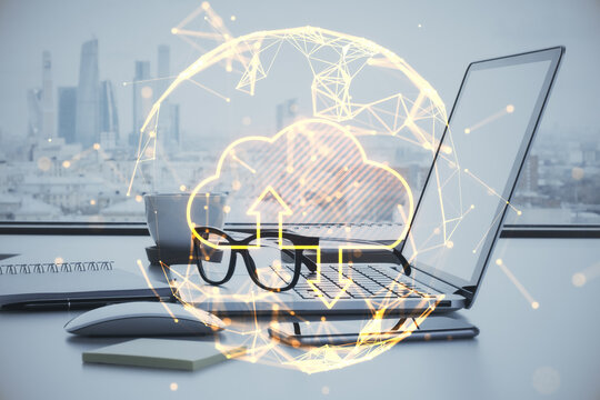 Close up of office workplace with laptop, other items, abstract glowing polygonal sphere with cloud and arrows on blurry city view background. Cloud computing and database concept. Double exposure.