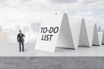 Obraz premium Attractive young european businessman looking at to-do list on concrete white city background. Checklist and busy concept.