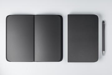 Top view on all-black notebooks with black empty pages and plain pen on white surface background. 3D rendering, mock up - obrazy, fototapety, plakaty