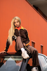 Fototapeta na wymiar Joven mujer afroamericana con cabello largo rubio y ropa deportiva sobre un fondo de color naranja