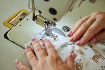 Industrial sewing production or atelier. The hands of tailors sewing fabrics on sewing machines to create clothes.