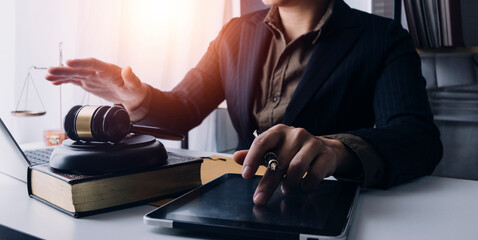Justice and law concept.Male judge in a courtroom with the gavel, working with, computer and docking keyboard, eyeglasses, on table in morning light