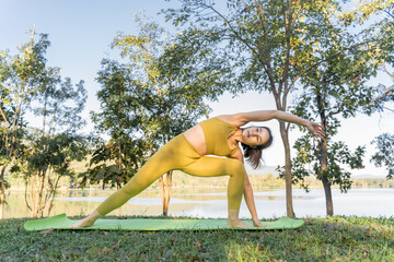 Young attractive and active woman practicing her morning yoga outdoor at a local lake park