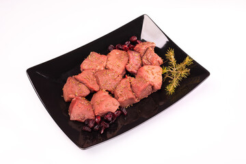Raw beef, game meat on a black plate, isolated. Pieces of red meat, top view. High quality roe,...