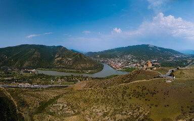 Fototapeta na wymiar Distance aerial wide panorama view of Jvari clifftop orthodox monastery located in Mtskheta Georgia. Summer day time. Travel and vacation concept. Copy space. Mtkvari river.