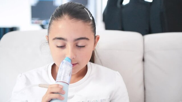 Young girl using a nebulizer inhaler device with mist shooting out of the mouthpiece - respiratory disease concept, slow motion
