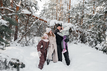 dad and mom and daughters have fun in the snowy forest