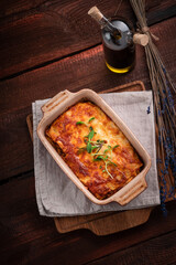 Lasagna with meat and tomato sauce baked in the oven in a ceramic dish. Homemade lasagna bolognese on a wooden table