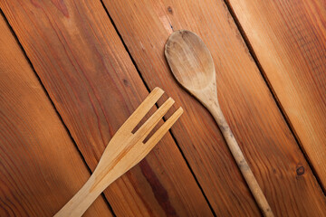A wooden fork and spoon lying on the top of a wooden table, top view.
