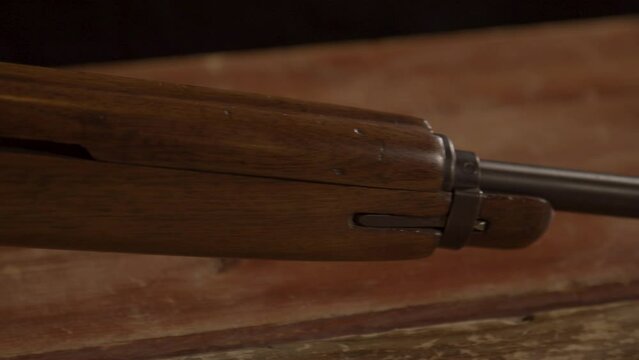 Close Dolly from barrel towards buttstock of classic .30 m1 carbine rifle standing on a wooden surface. The M1 carbine was introduced during WW2 and used in many conflicts afterwards