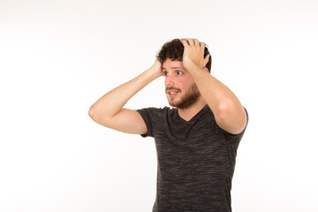 young bearded man caught with his hands on his head on a white background