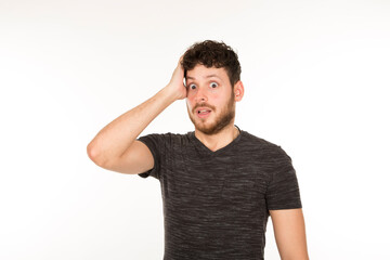 young bearded man with hand on head with expression of surprise and astonishment on white background